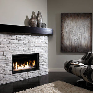 Kingsman ZCVRB3622 36-inch linear gas fireplace in a white stacked stone wall with a dark wood mantel
