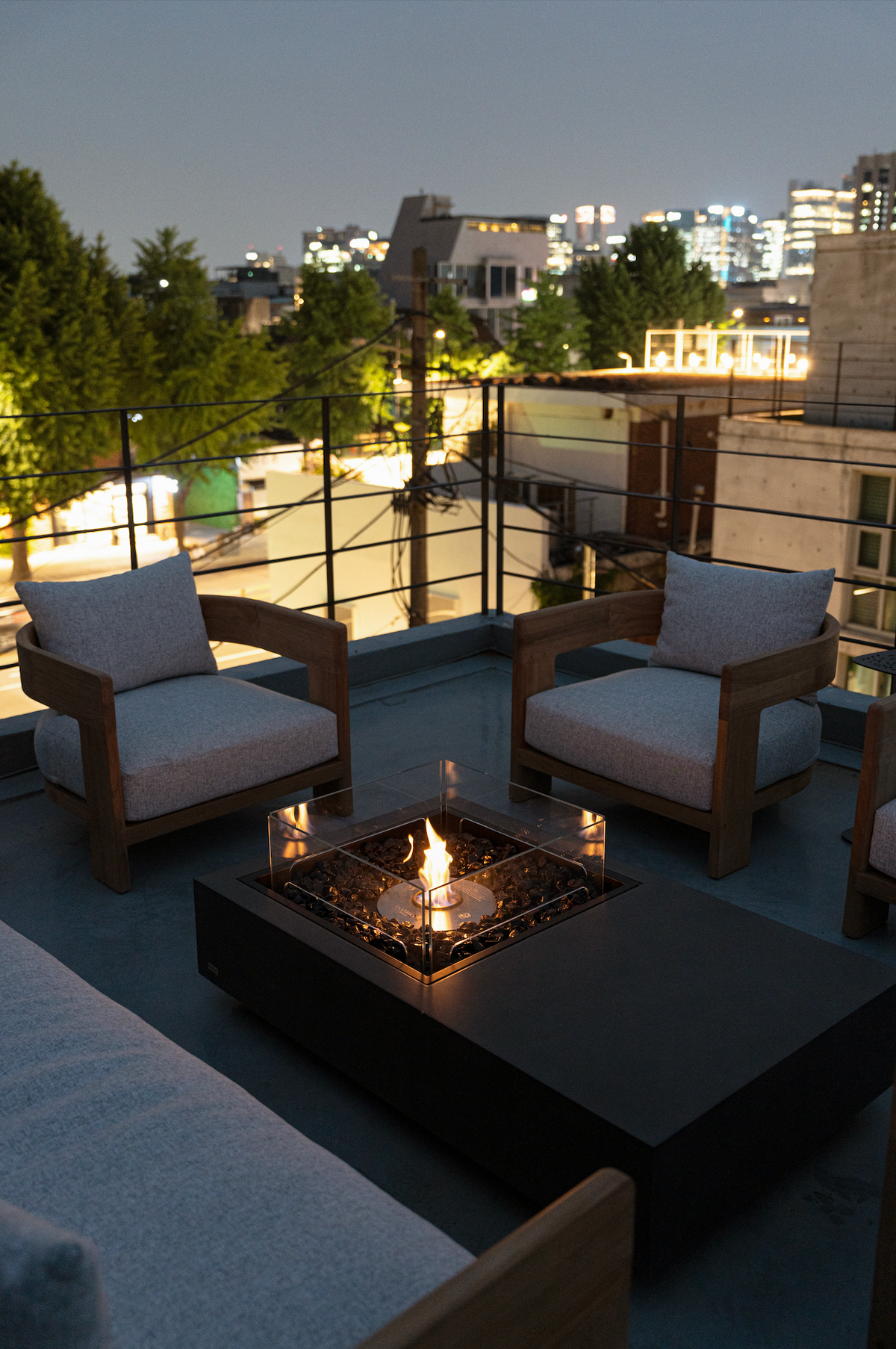 EcoSmart Fire Manhattan 50 fire table on a city rooftop terrace at dusk with lounge chairs