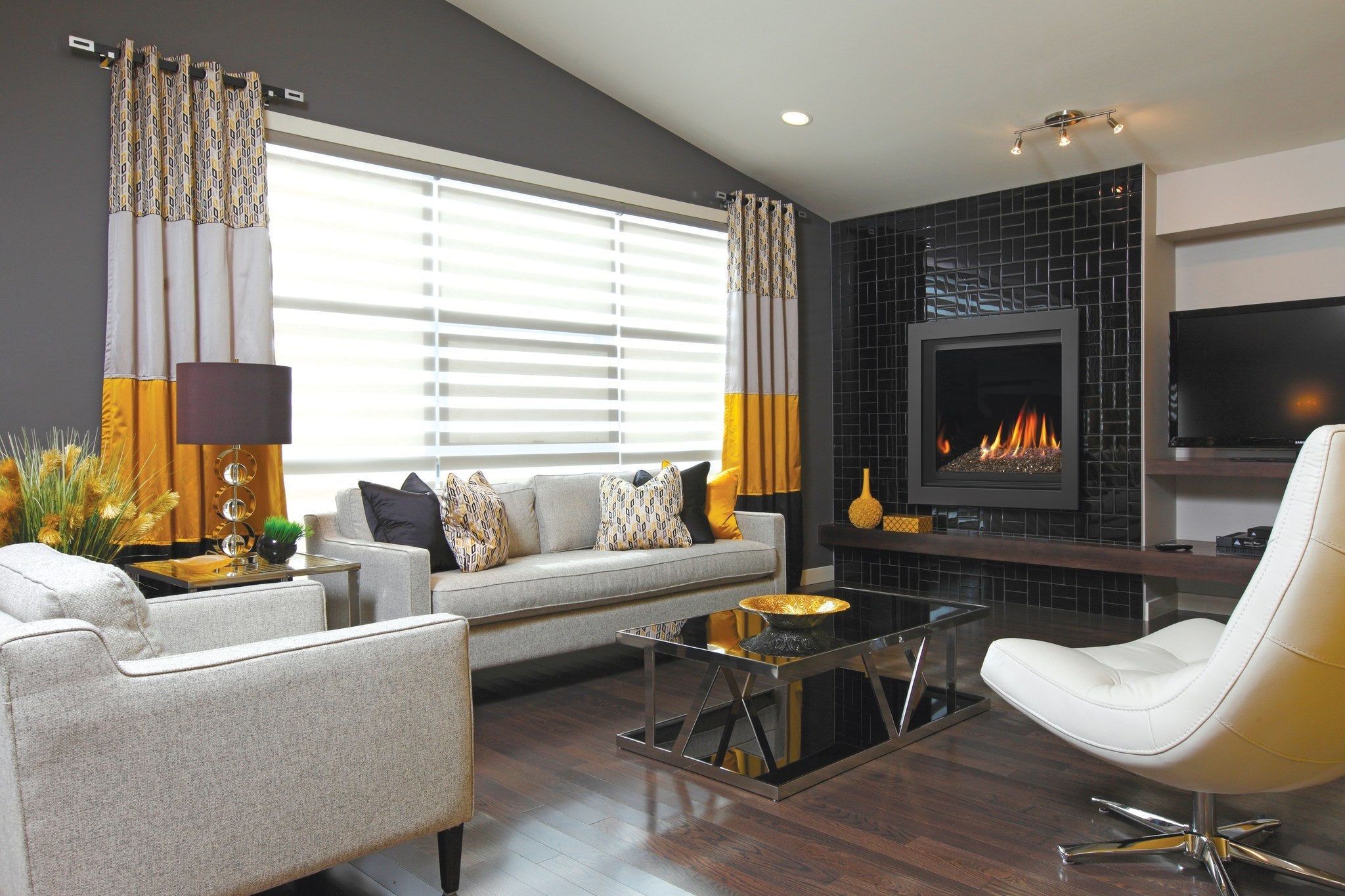 Kingsman Bentley zero clearance direct vent gas fireplace with ember glass media on the glass tray, set into a black tiled feature wall in a modern living room